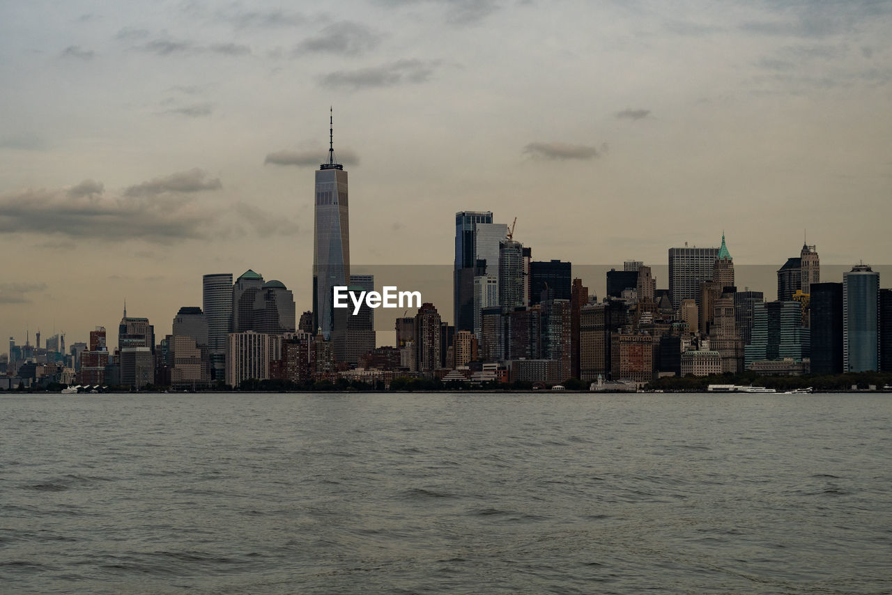 Sea by buildings in city against sky