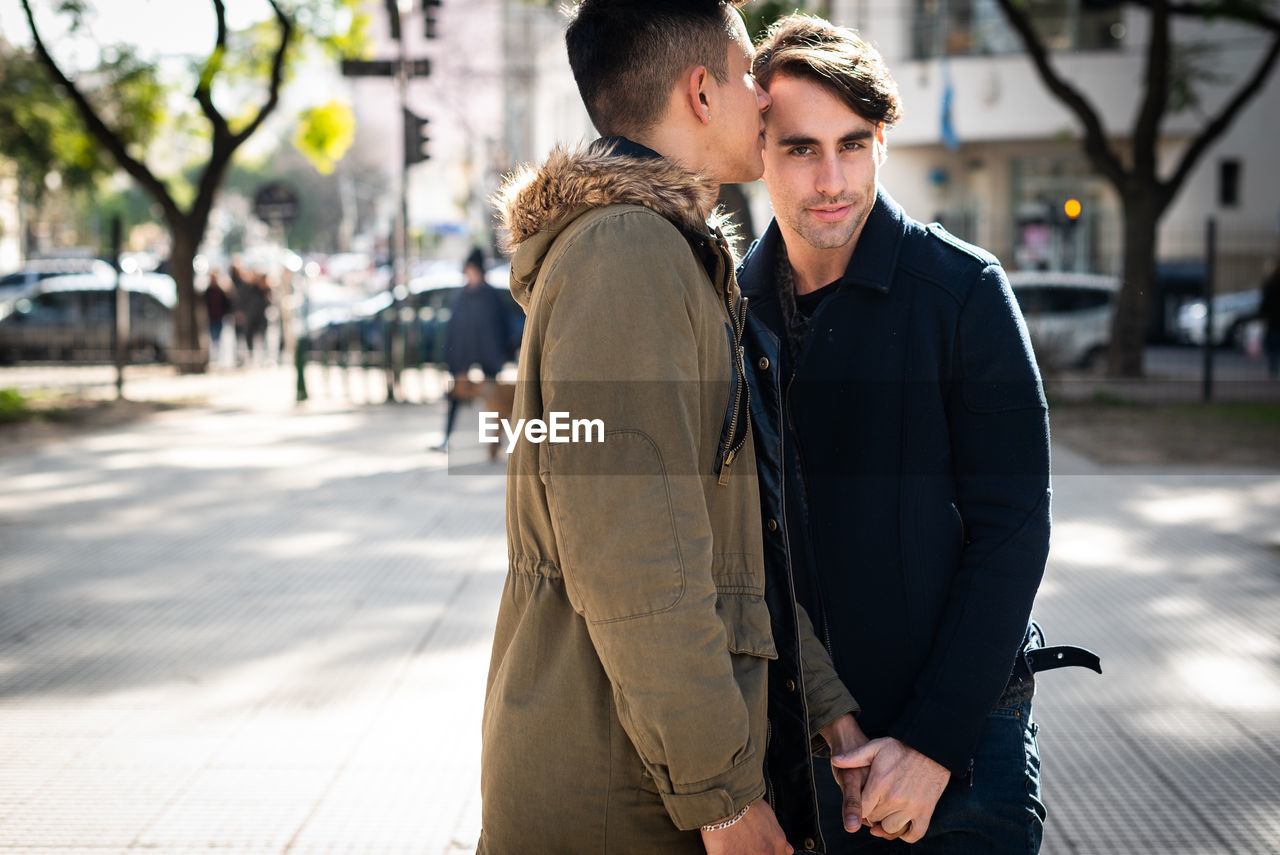 Homosexual couple kissing on street in city