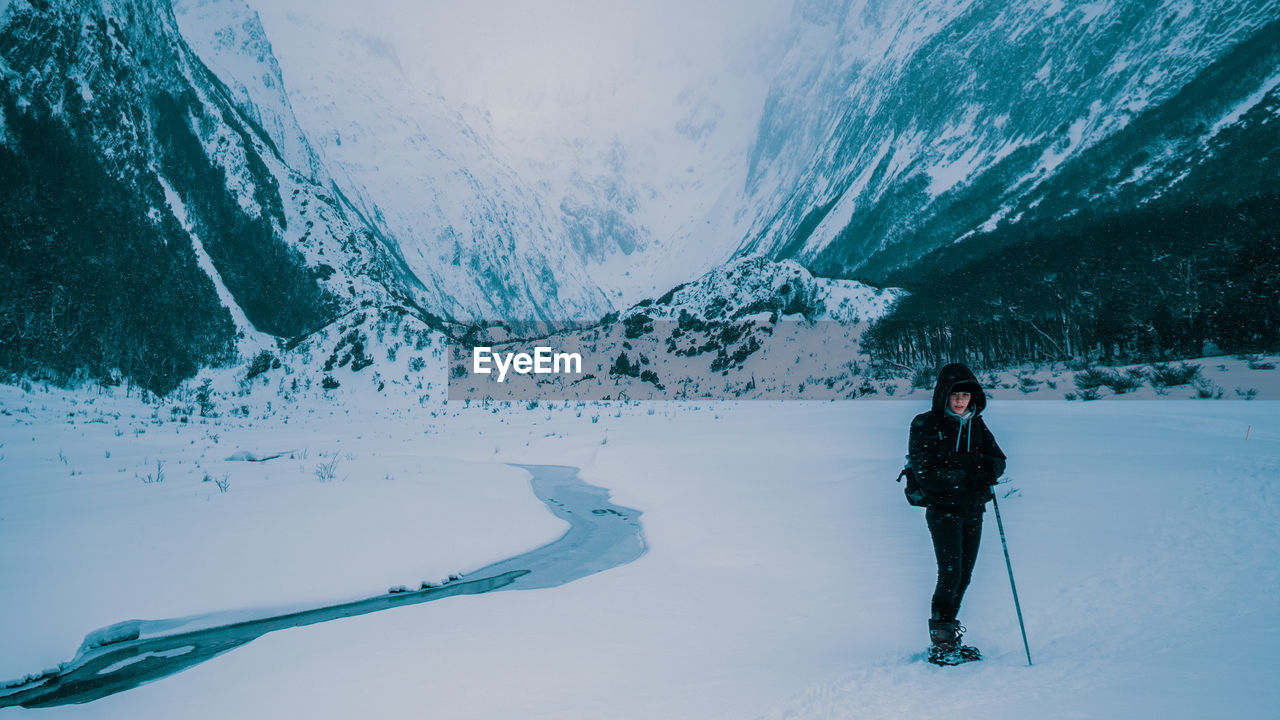 Full length of woman standing on snow covered land against mountain