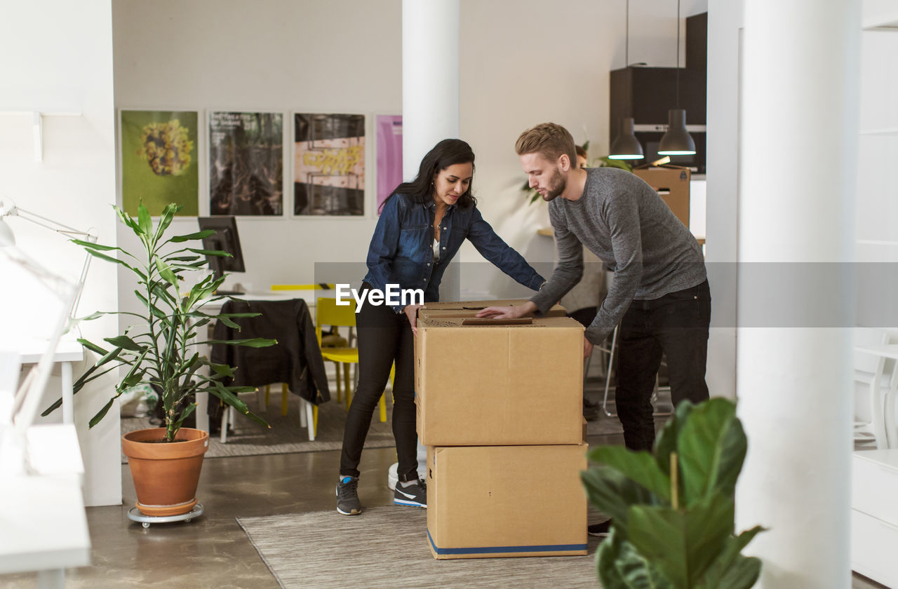 Multi-ethnic business colleagues moving cardboard boxes in creative office