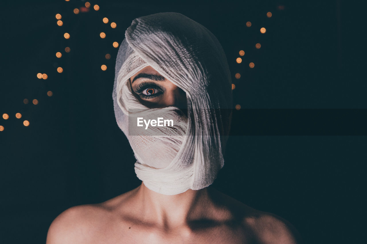 Close-up portrait of woman face covered with fabric at night