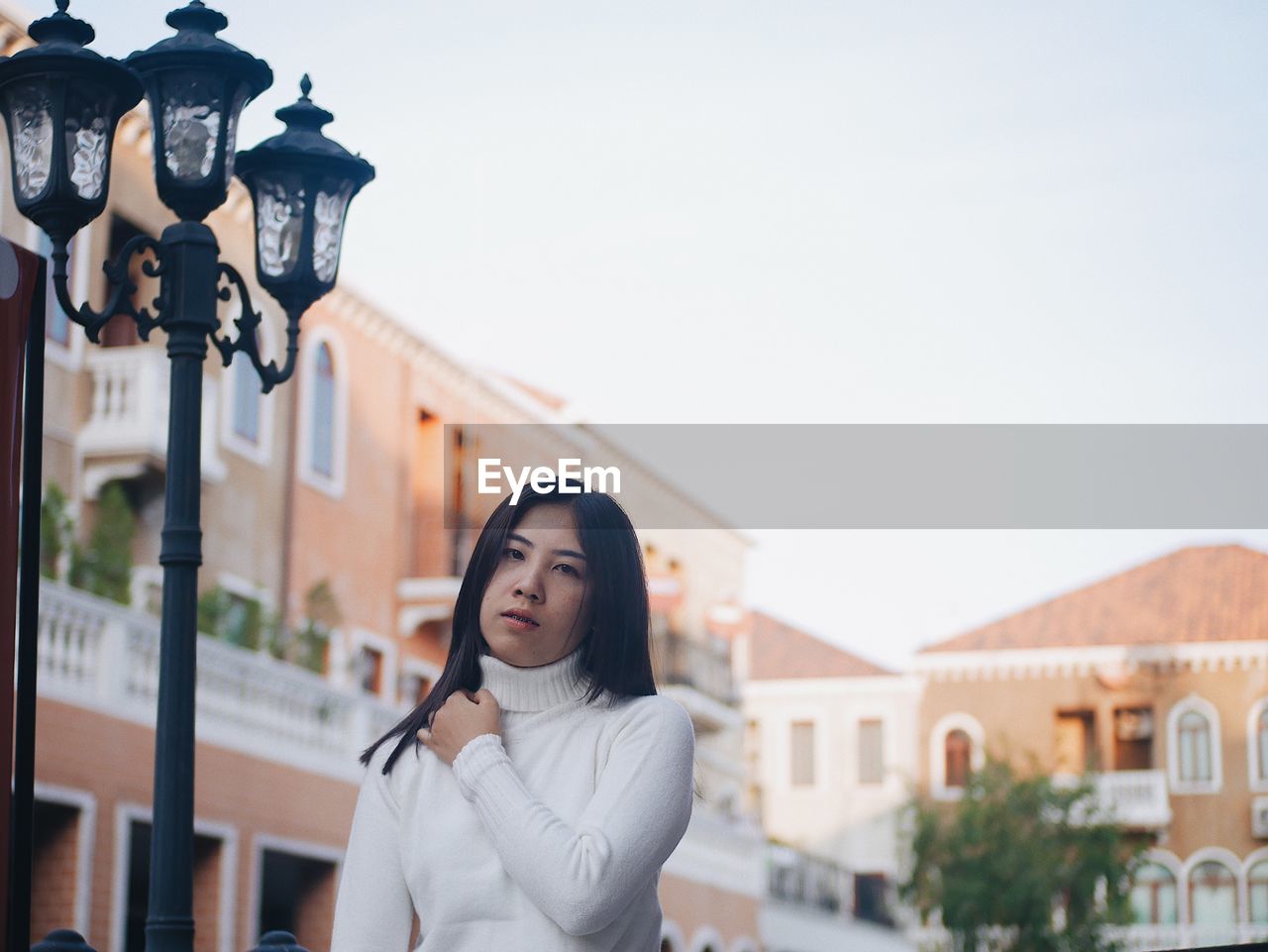 Portrait of young woman standing against buildings in city