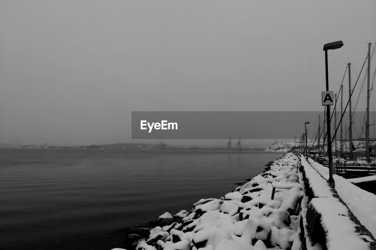 Scenic view of sea with snow covered shore against clear sky