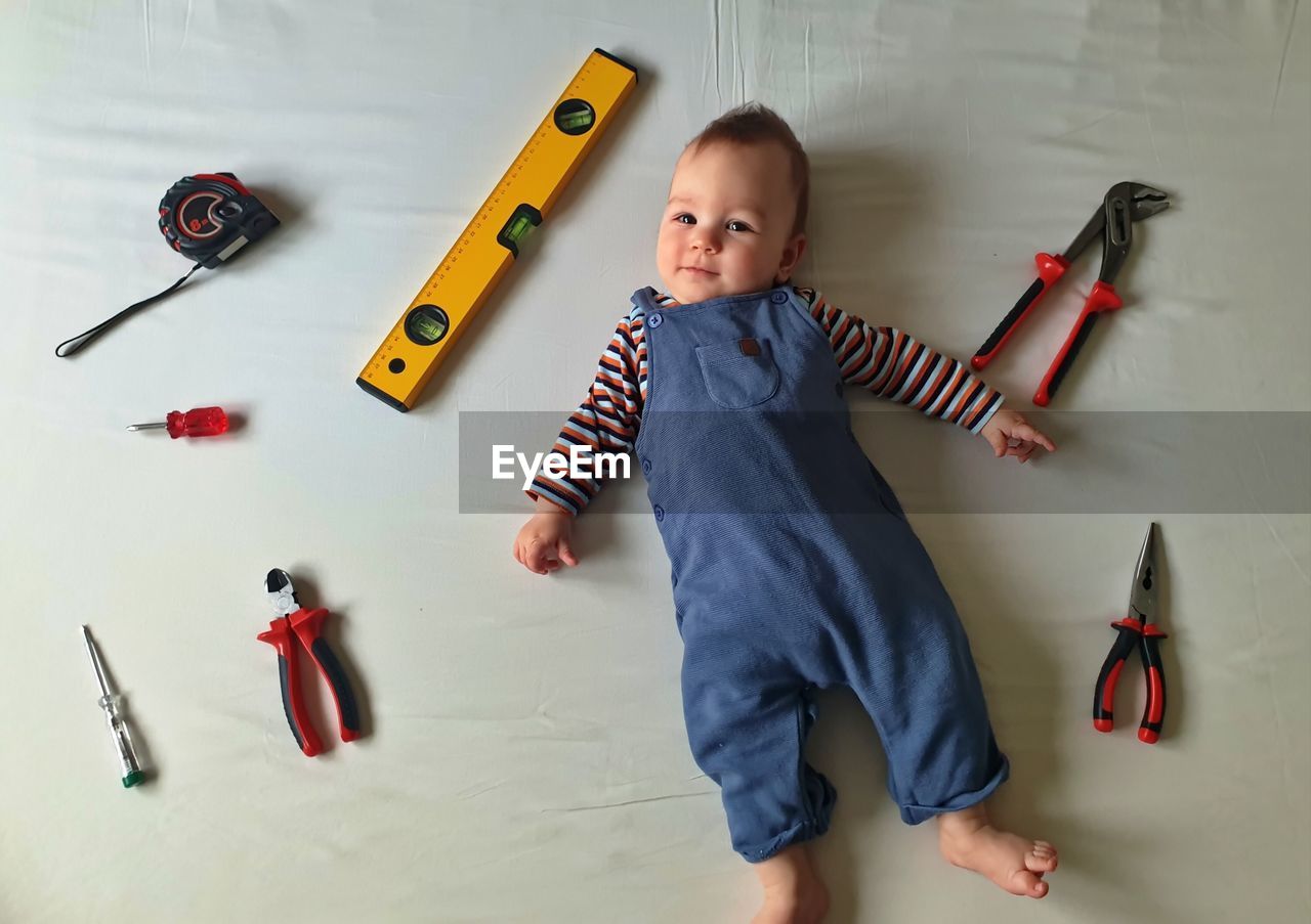 Flat lay of cute baby with mechanic tools