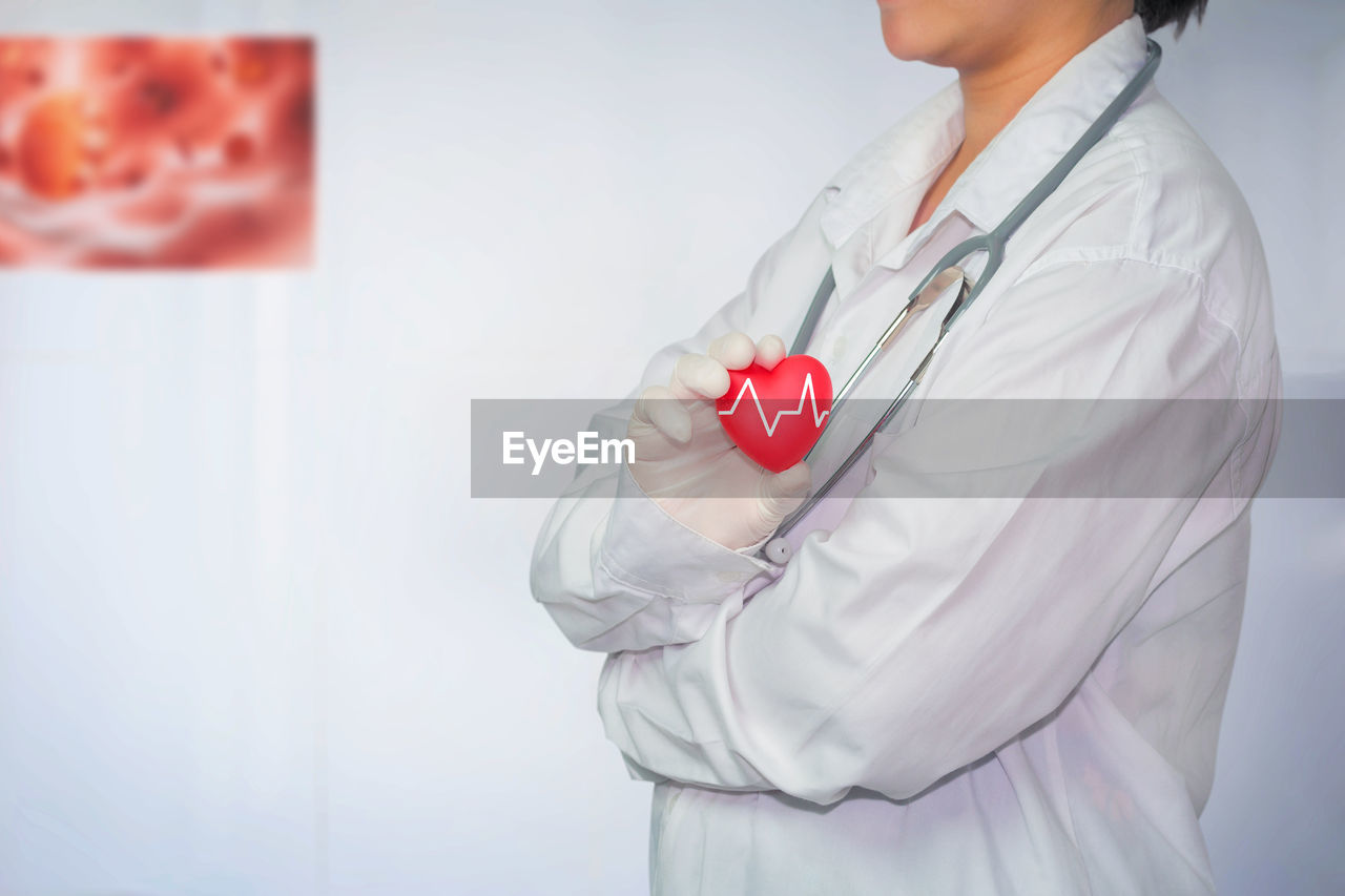 Midsection of female doctor holding heart shape at hospital