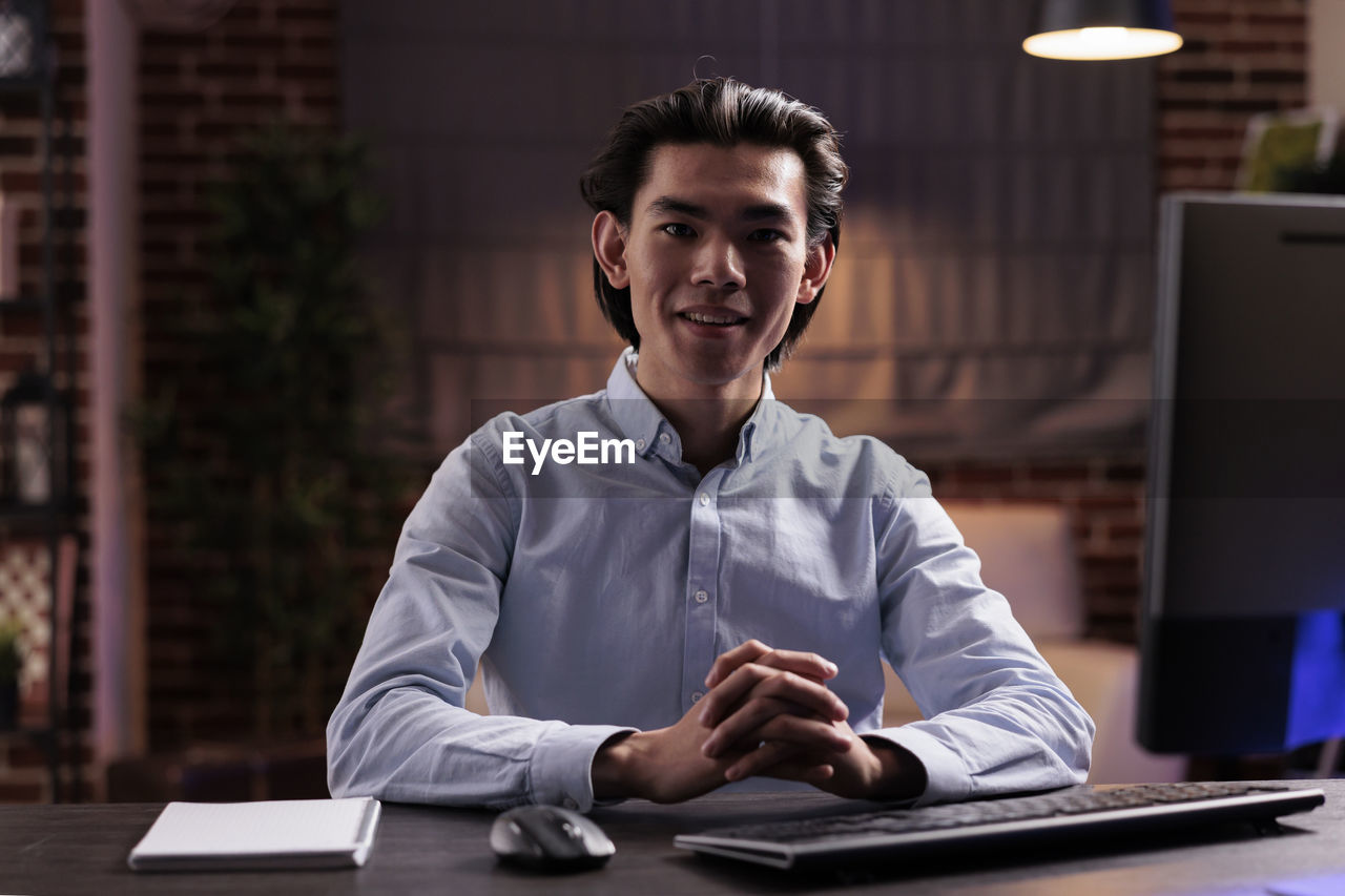 portrait of young man using laptop at desk in office