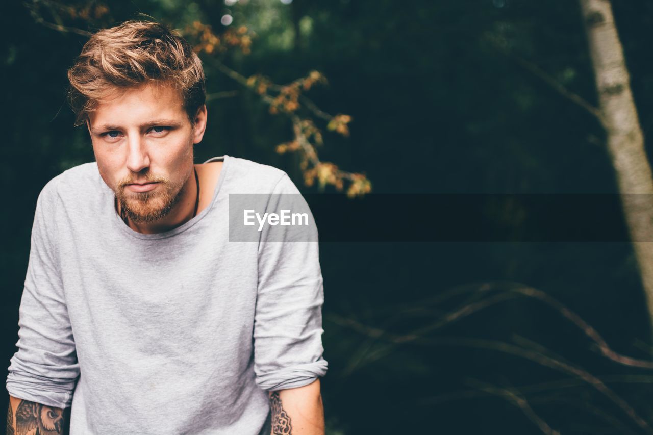 Portrait of young man against trees