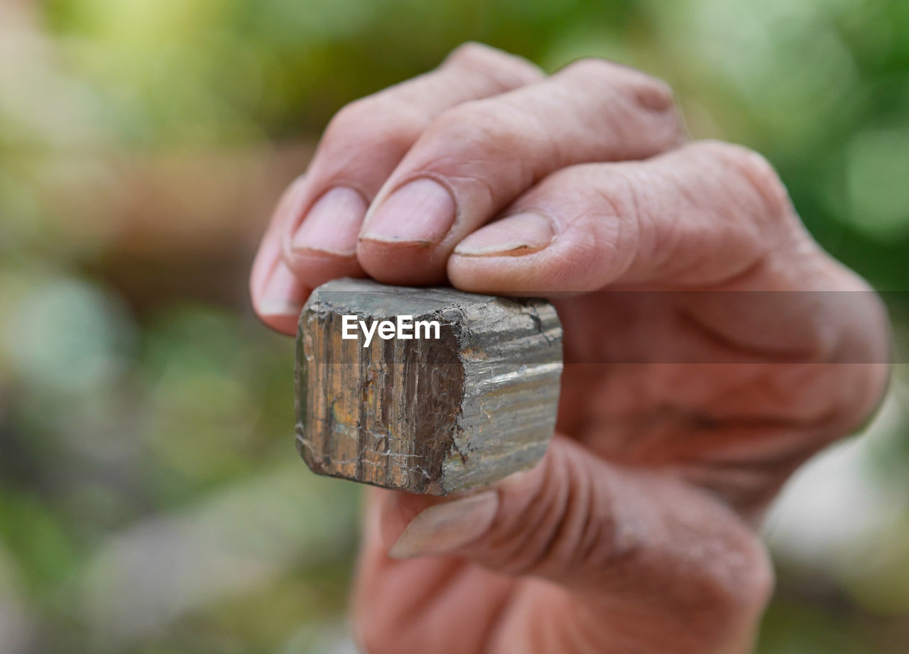 Close-up of human hand holding rusty metal