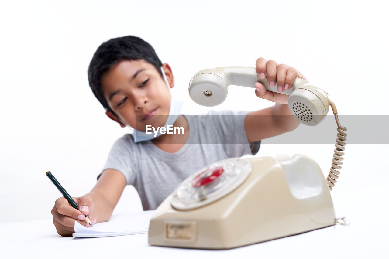 Schoolboy talking on the telephone during online class at home