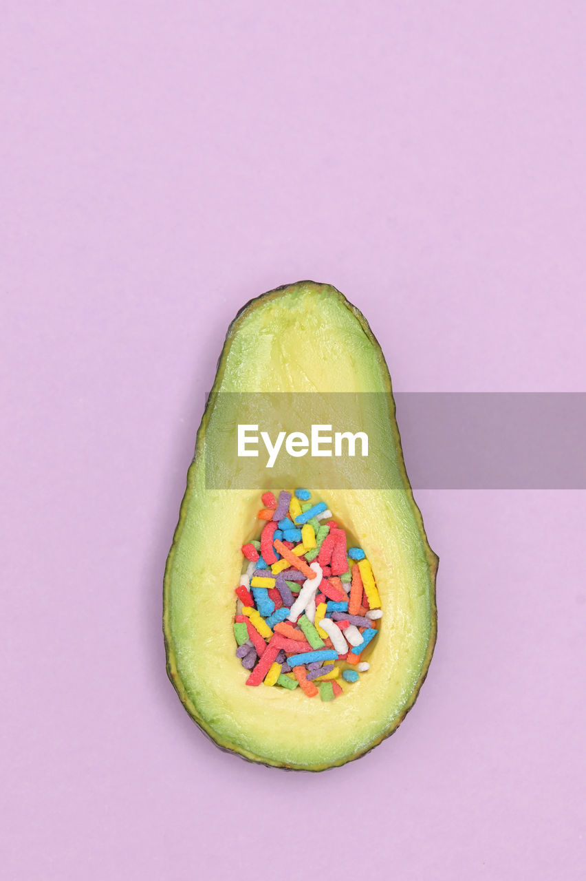 Slice of avocado cut in half and sprinkles candy