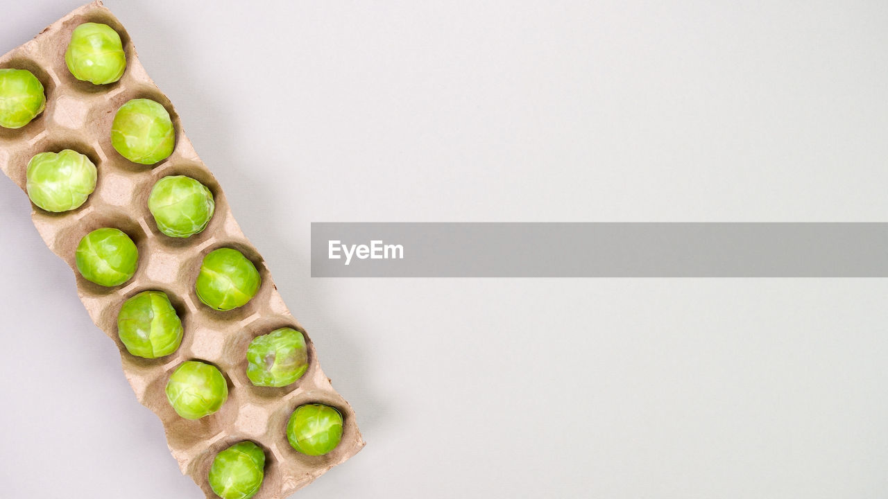 High angle view of raw organic brussel sprouts in brown pack on grey background