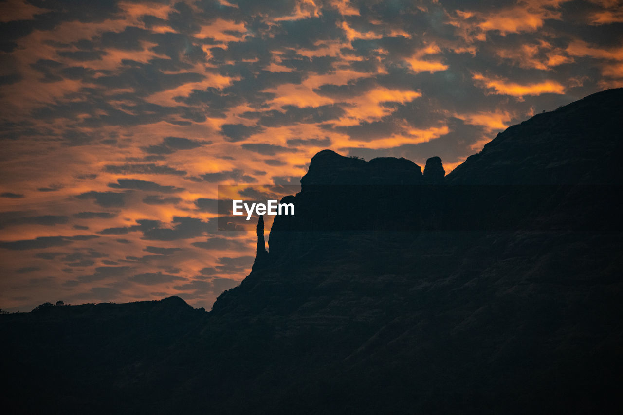 Low angle view of silhouette mountain against dramatic sky