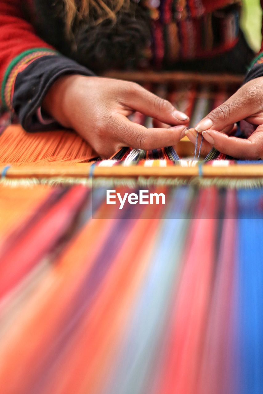 Midsection of person weaving loom