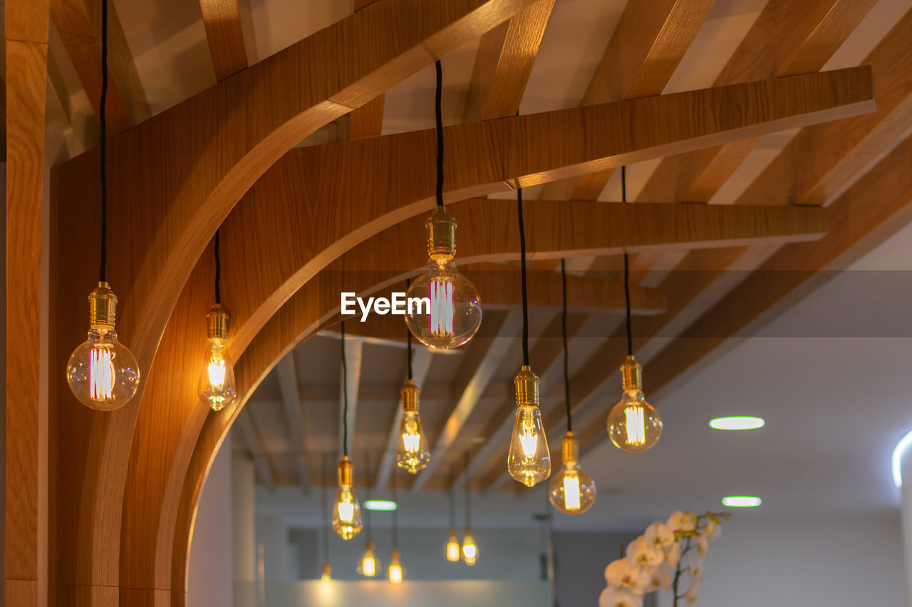 LOW ANGLE VIEW OF ILLUMINATED CHANDELIER HANGING ON CEILING