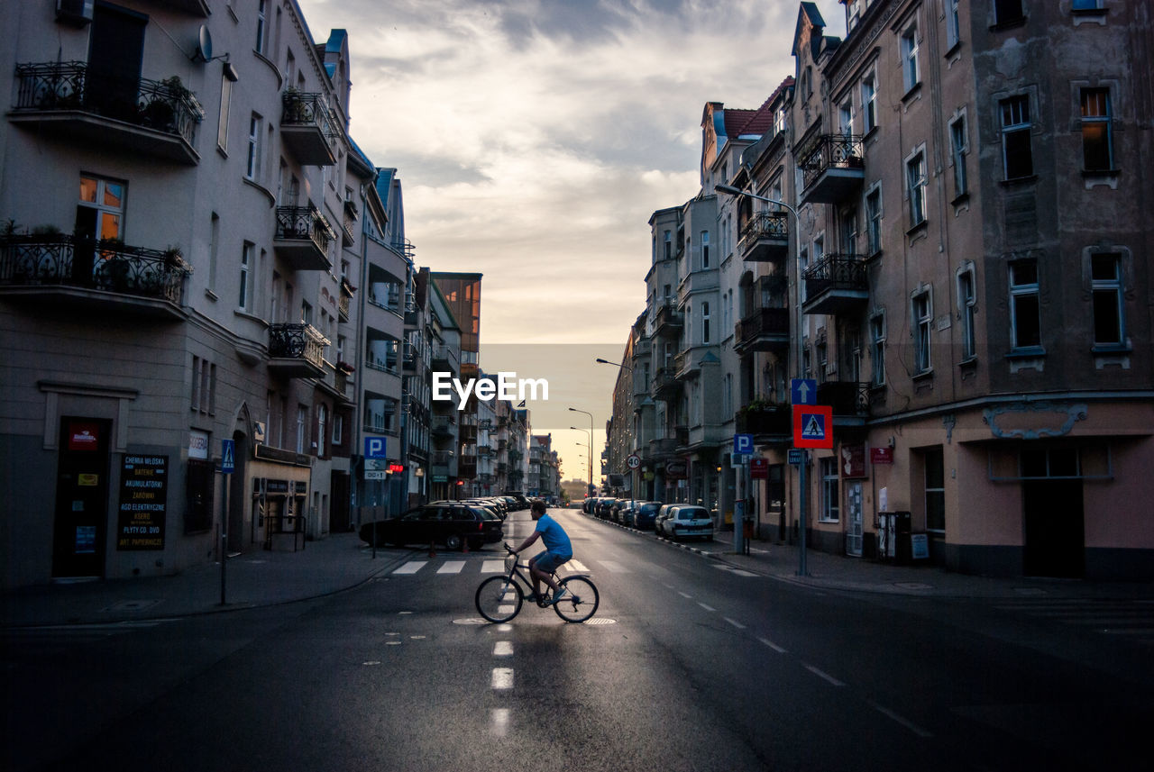 Side view of man riding bicycle on road in city