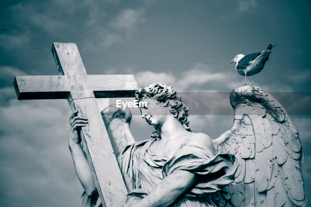 LOW ANGLE VIEW OF ANGEL STATUE AGAINST CLOUDY SKY