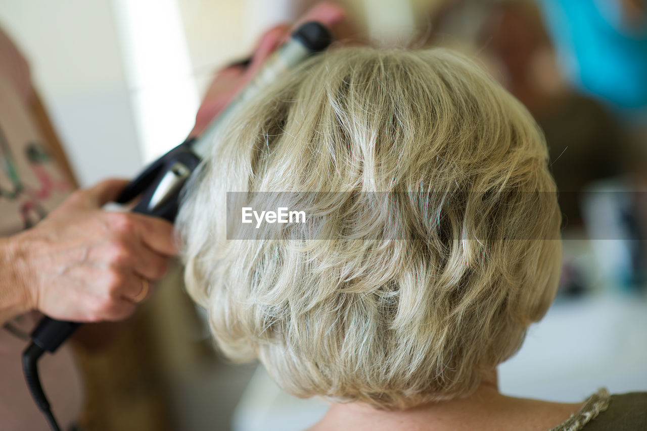 Cropped image of hairdresser styling customer hair in salon