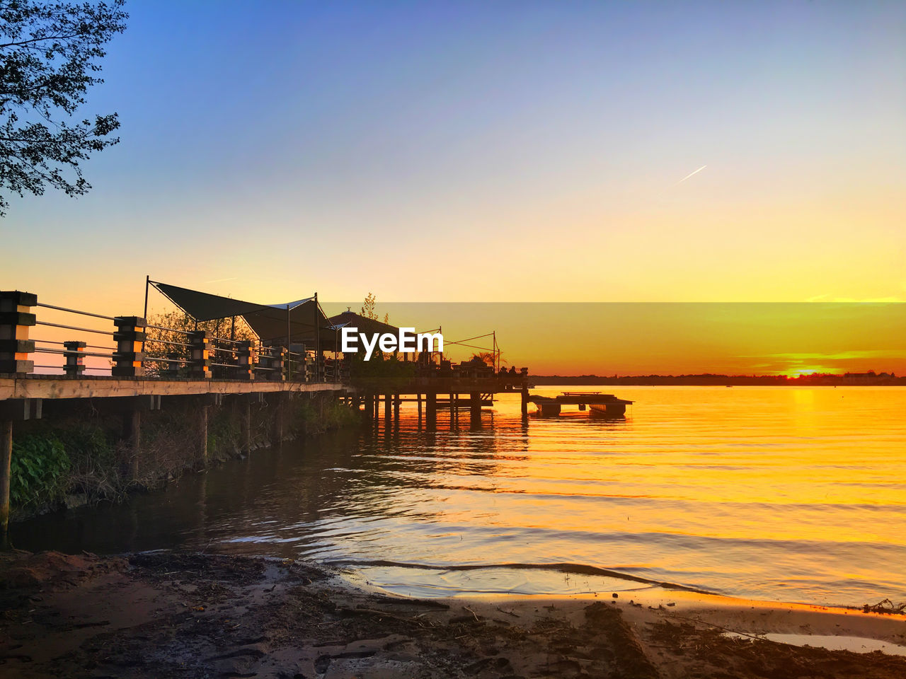 Pier in sea at sunset