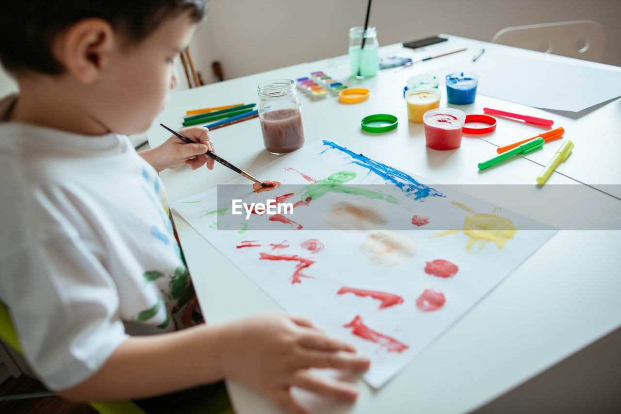 Boy doing painting while sitting at home