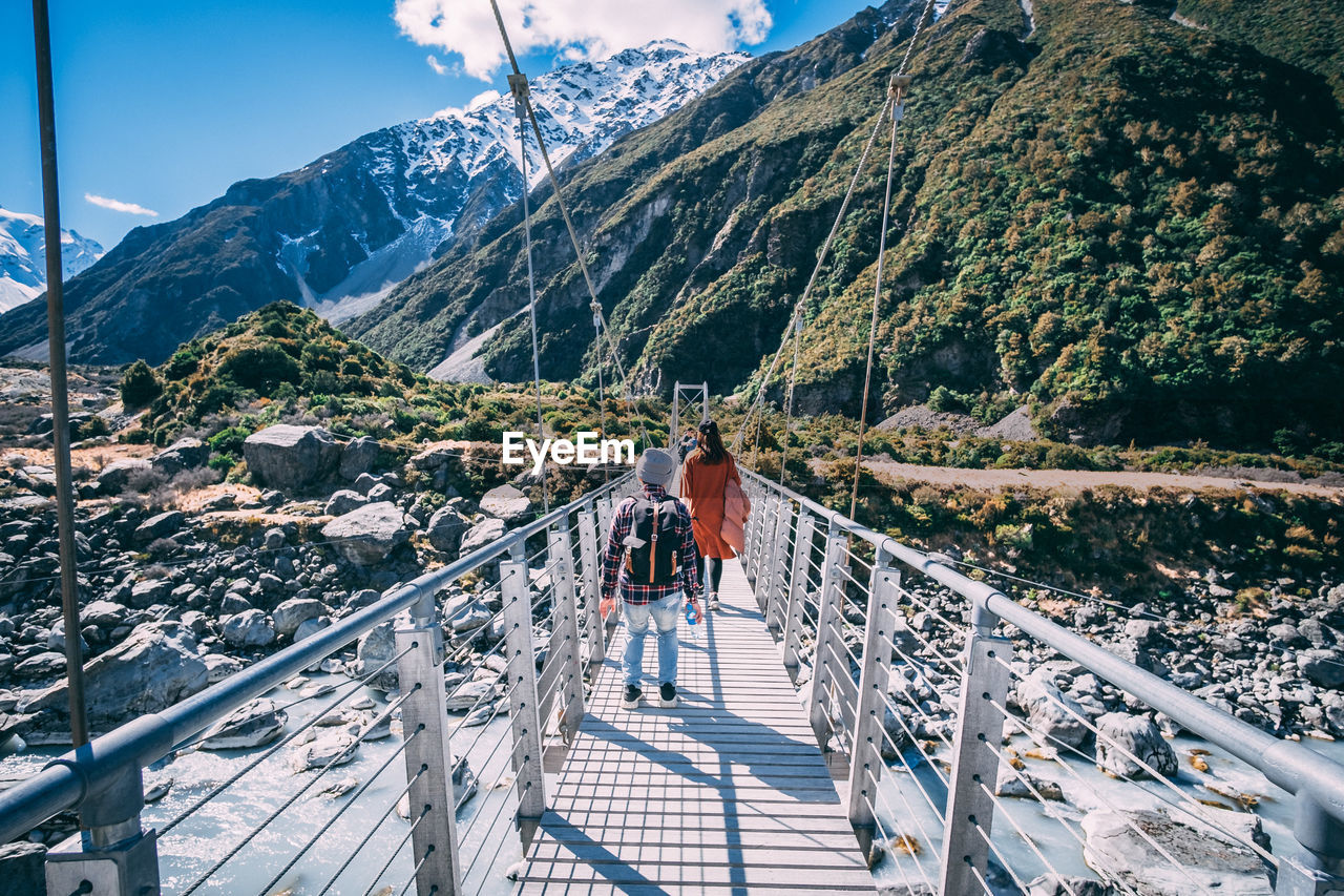 Rear view of woman and man walking on footbridge