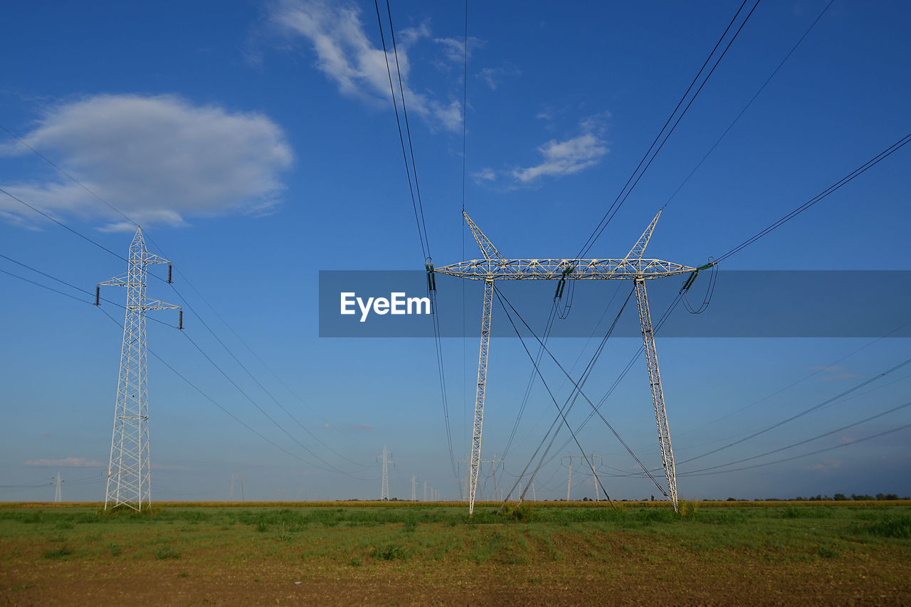 Row of transmission lines against blue cloudy sky