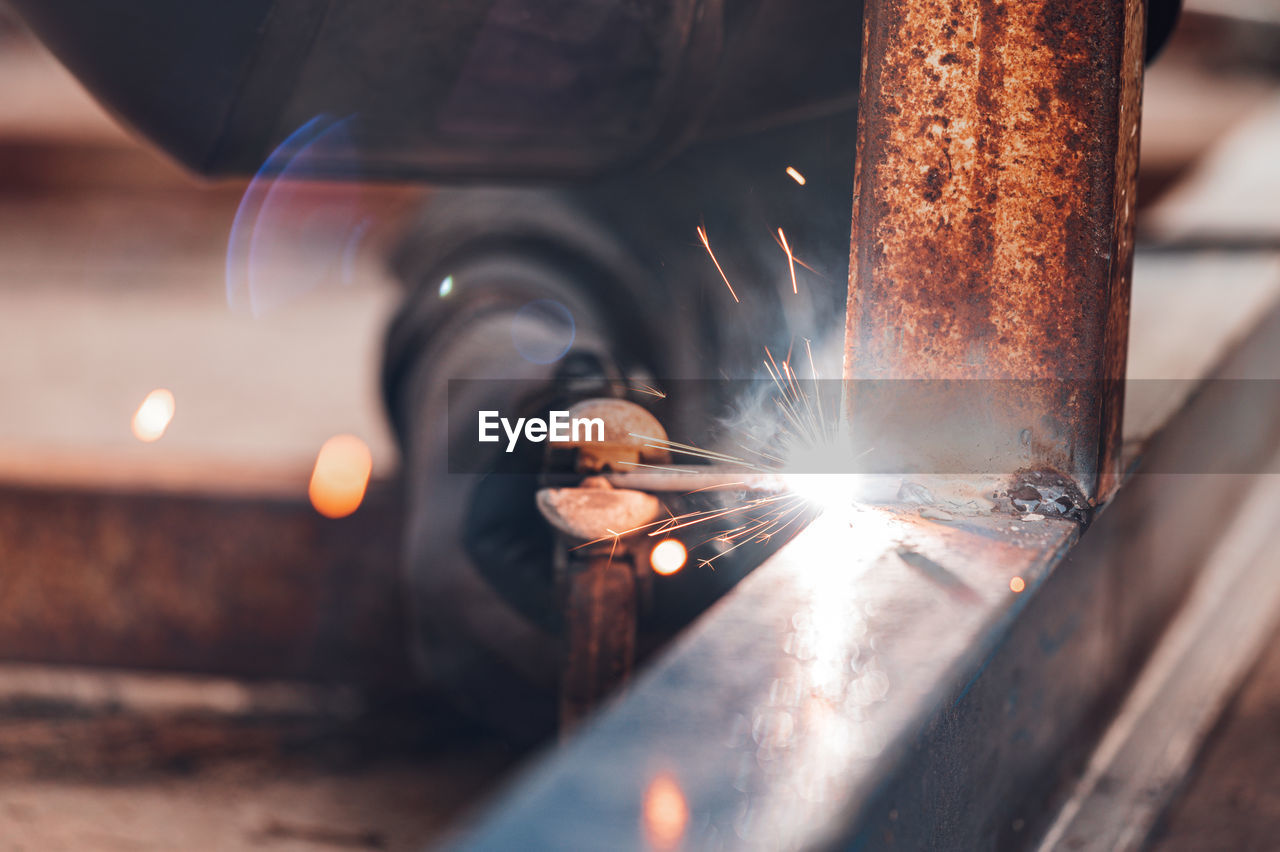 CLOSE-UP OF MAN WORKING ON METAL IN ILLUMINATED