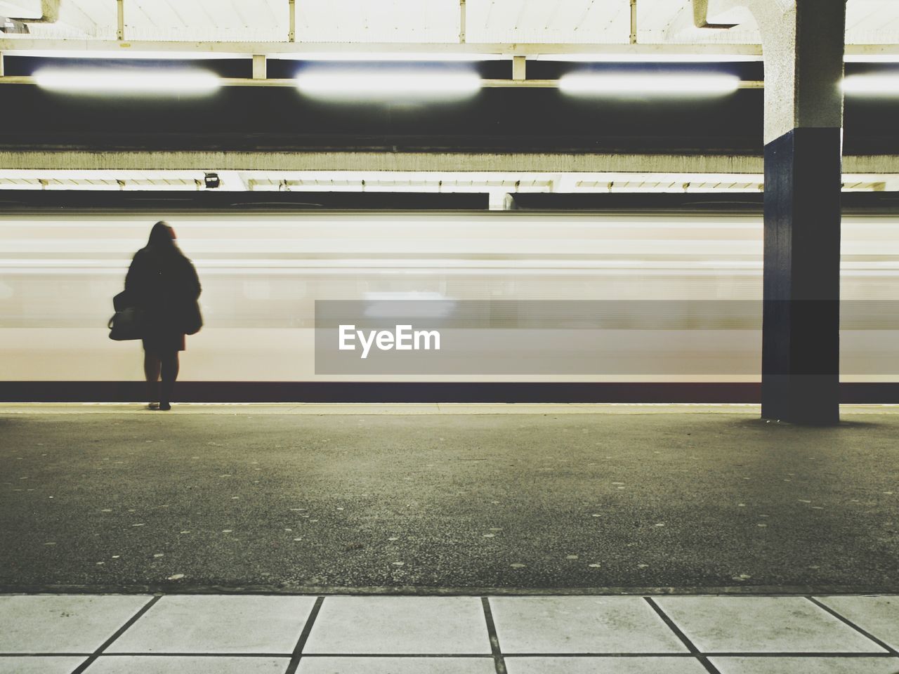 Rear view of woman standing at railroad station