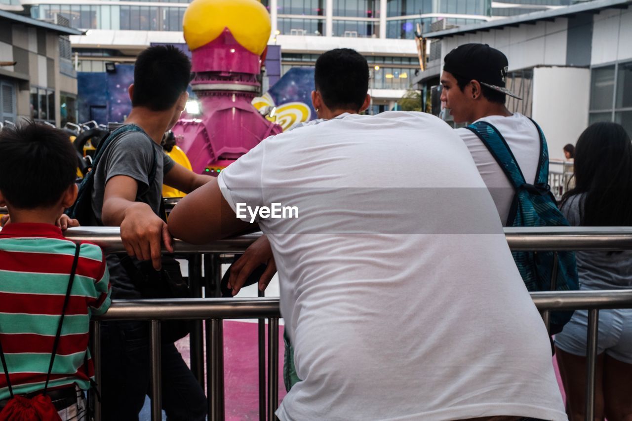 REAR VIEW OF PEOPLE SITTING ON CHAIR