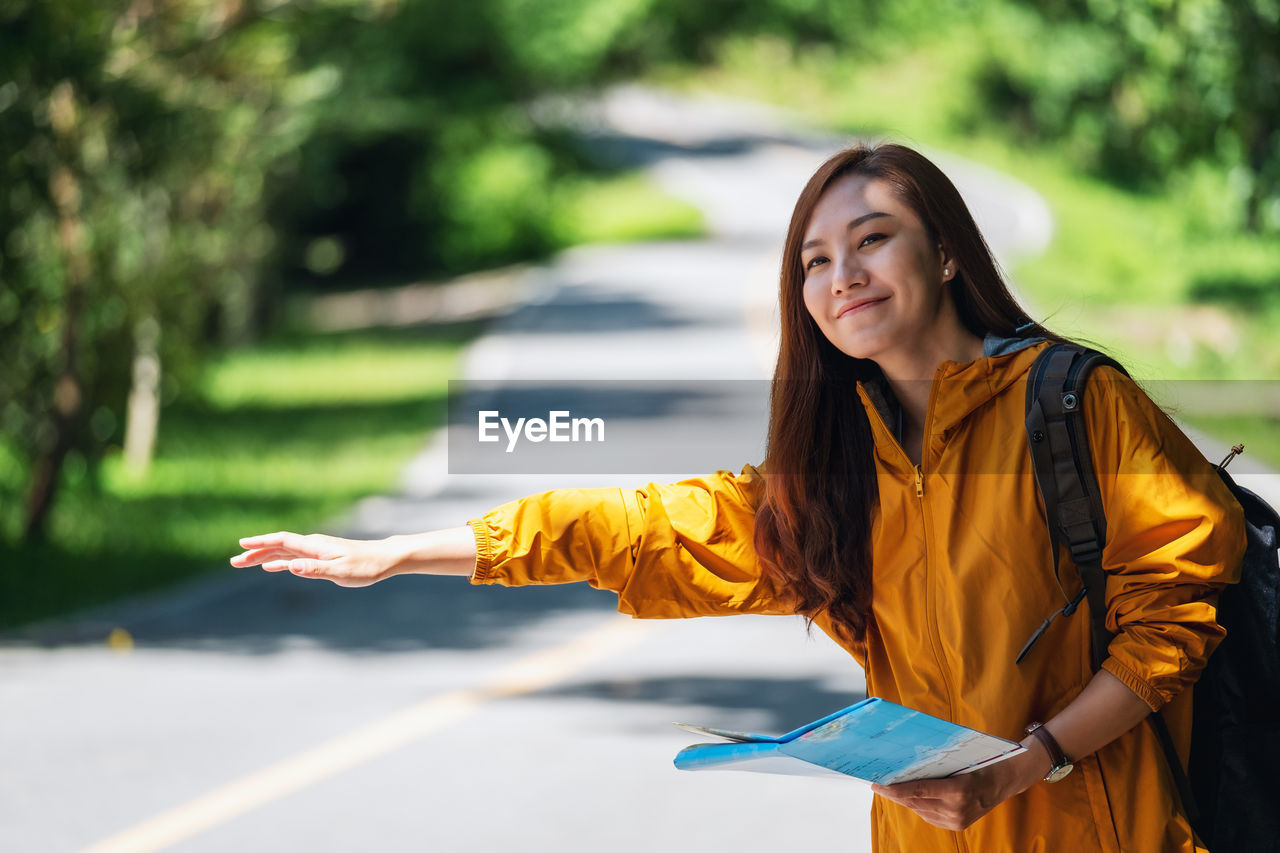 Young woman with arms raised standing outdoors