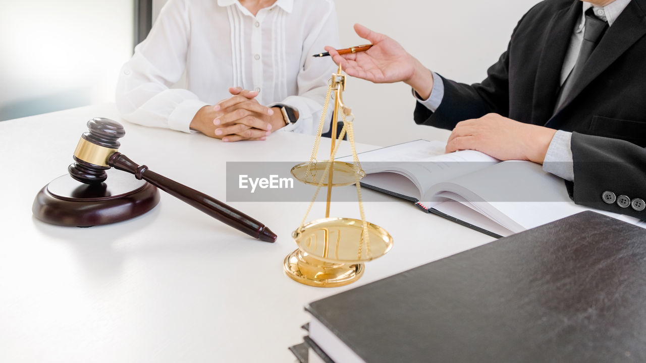 Lawyer talking to female while sitting by table in office