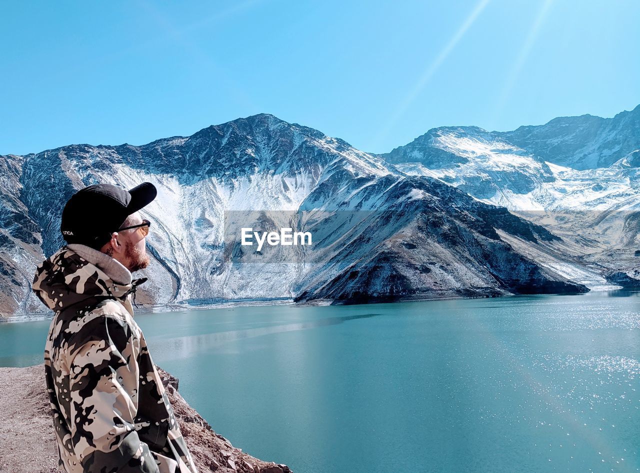WOMAN WITH SNOWCAPPED MOUNTAIN AGAINST SKY
