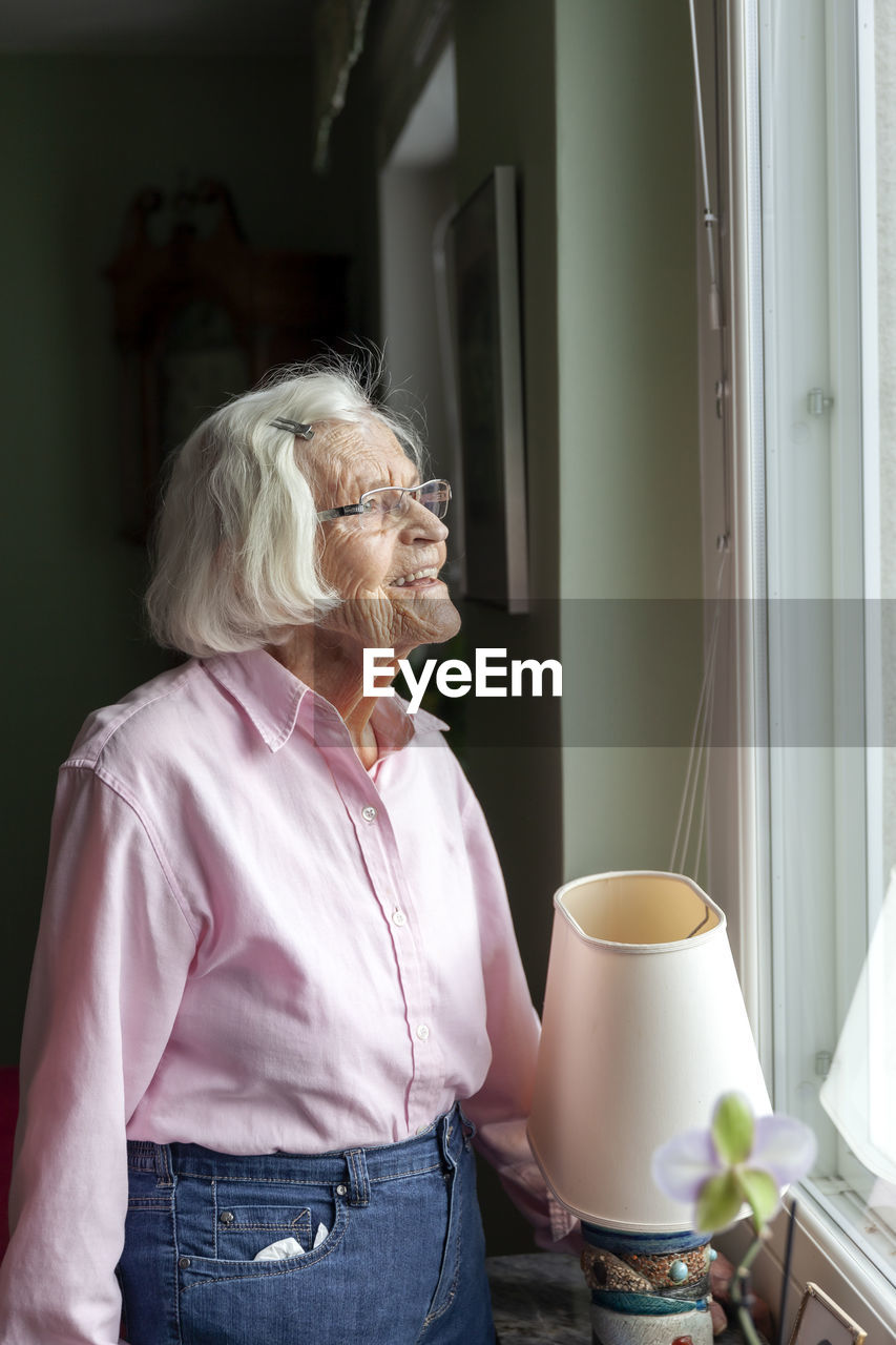 Senior woman looking through window