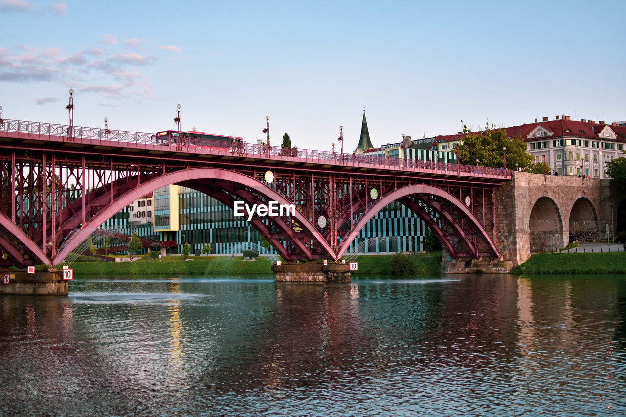 Bridge over river in city against sky