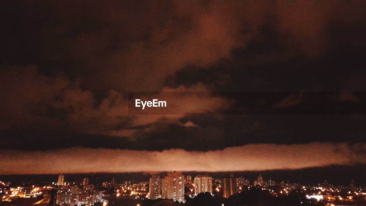 PANORAMIC VIEW OF ILLUMINATED CITY AGAINST SKY AT NIGHT