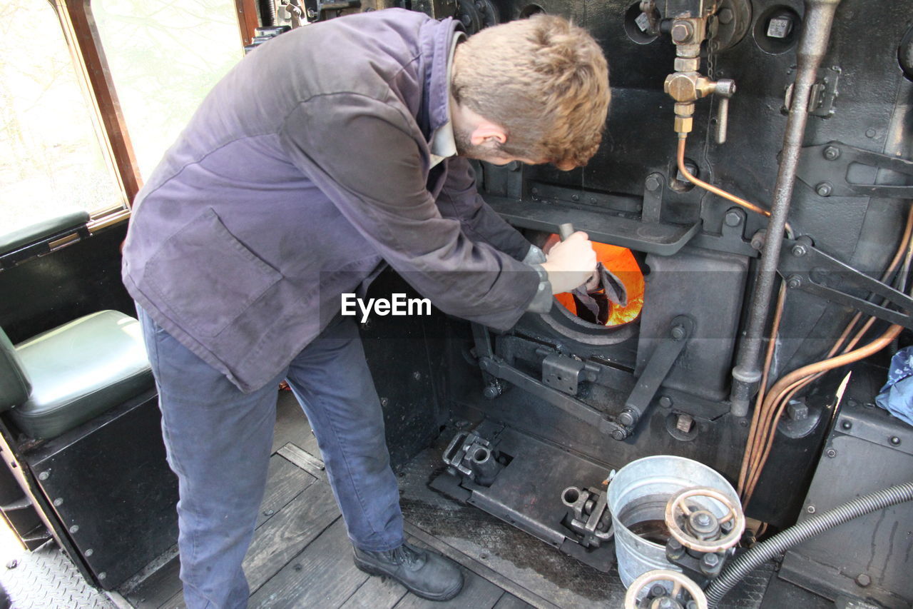 High angle view of train engineer working in steam train