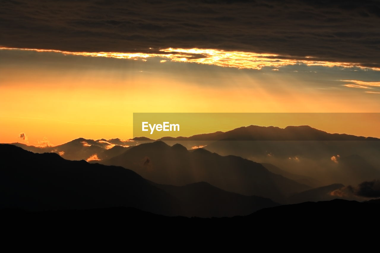 Scenic view of silhouette mountains against orange sky