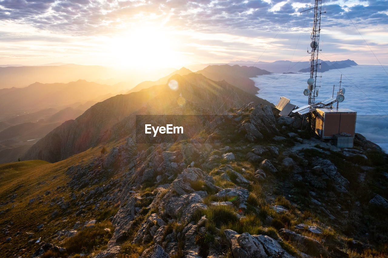 Summit view during sunrise of mountain ridges with telecommunication towers and sea of clouds