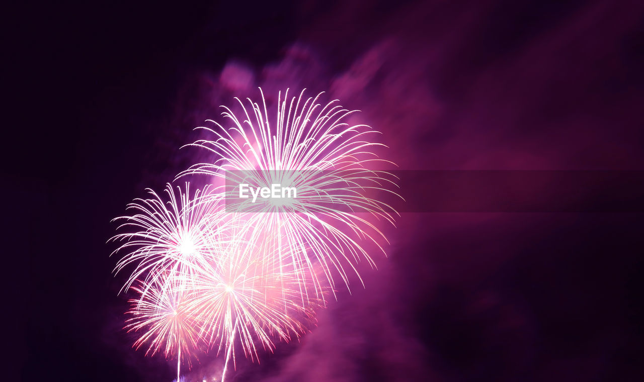 Fantastic magenta purple fireworks exploding into the city night sky