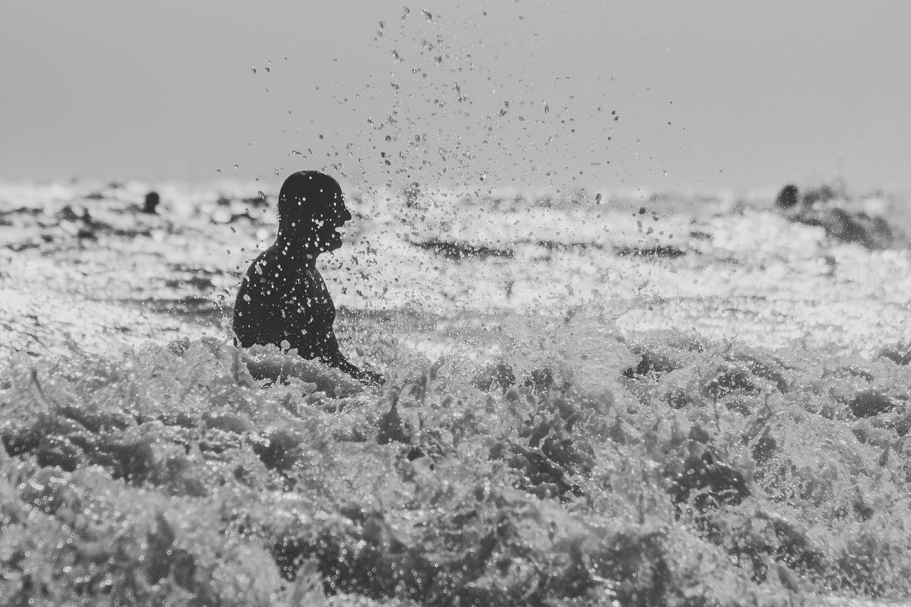 Man standing with waves in sea