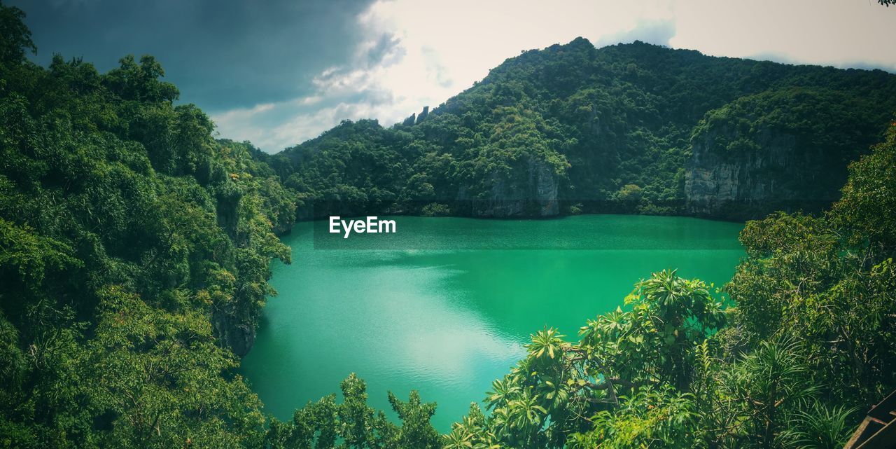 Scenic view of emerald green lake with mountains against sky - thailand