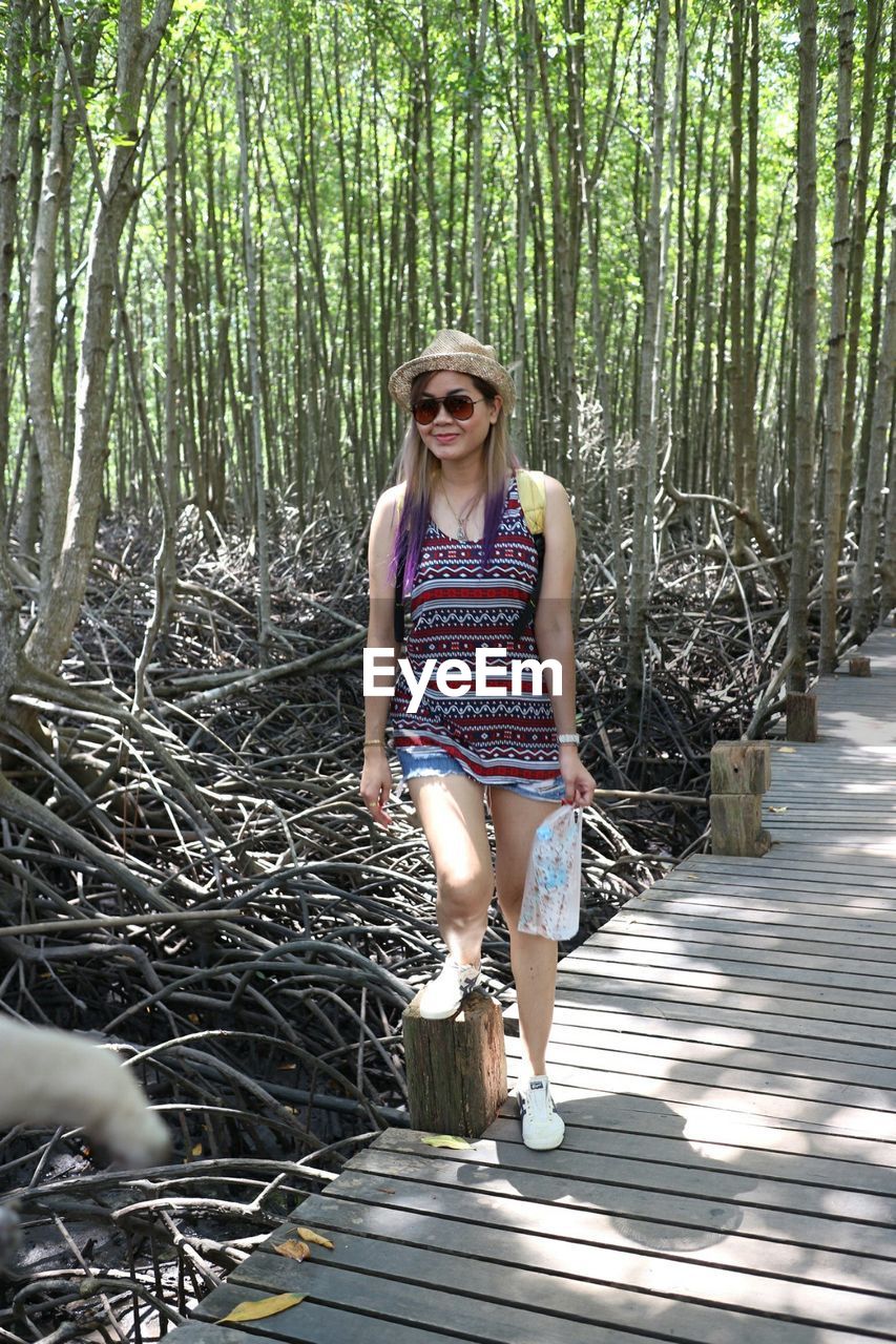 Full length of woman standing on boardwalk in forest