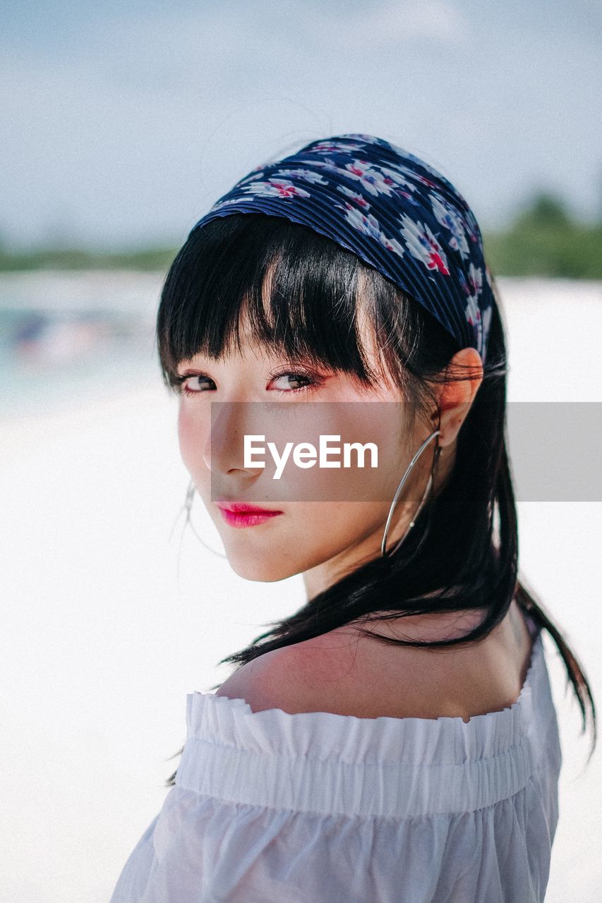 Close-up portrait of beautiful woman standing at beach