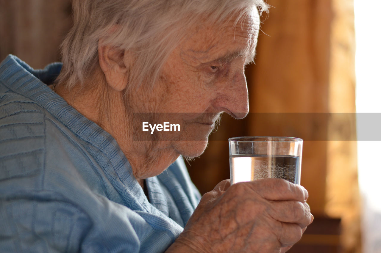 Eldery woman who drinks water from a glass. loneliness, stress, missing grandchildren. 