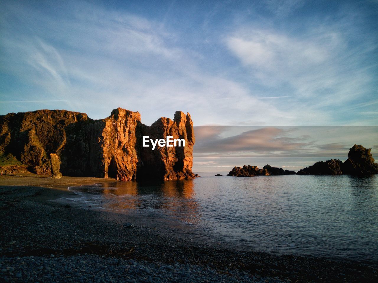 Rock formation by sea against sky