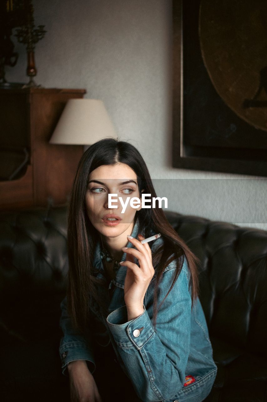 Young woman smoking while sitting at home