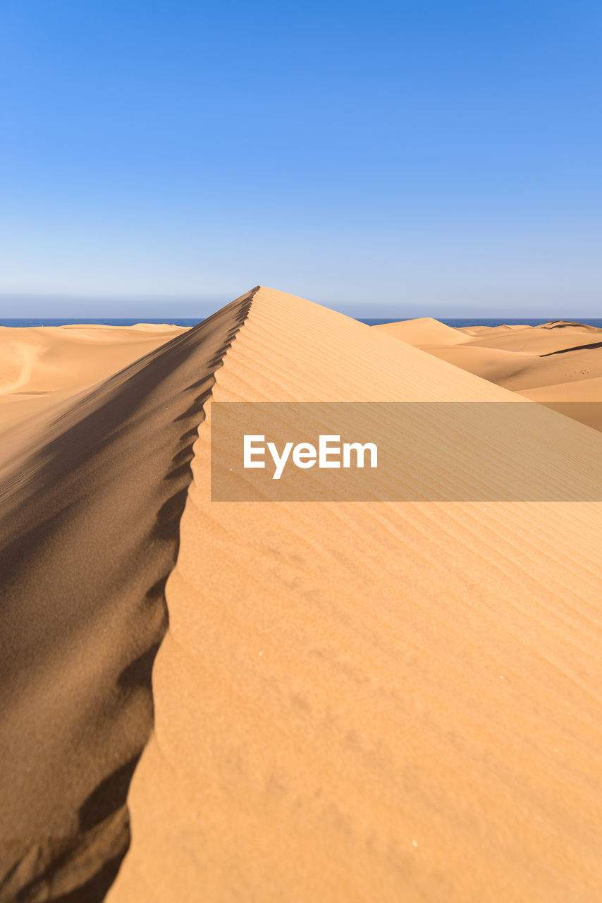 Scenic view of desert against clear blue sky