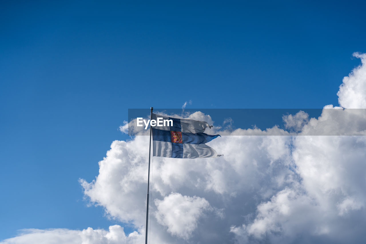 LOW ANGLE VIEW OF FLAGS AGAINST CLOUDY SKY