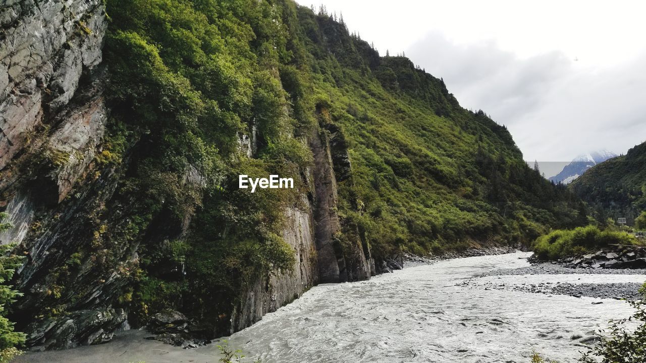 SCENIC VIEW OF WATERFALL BY MOUNTAINS