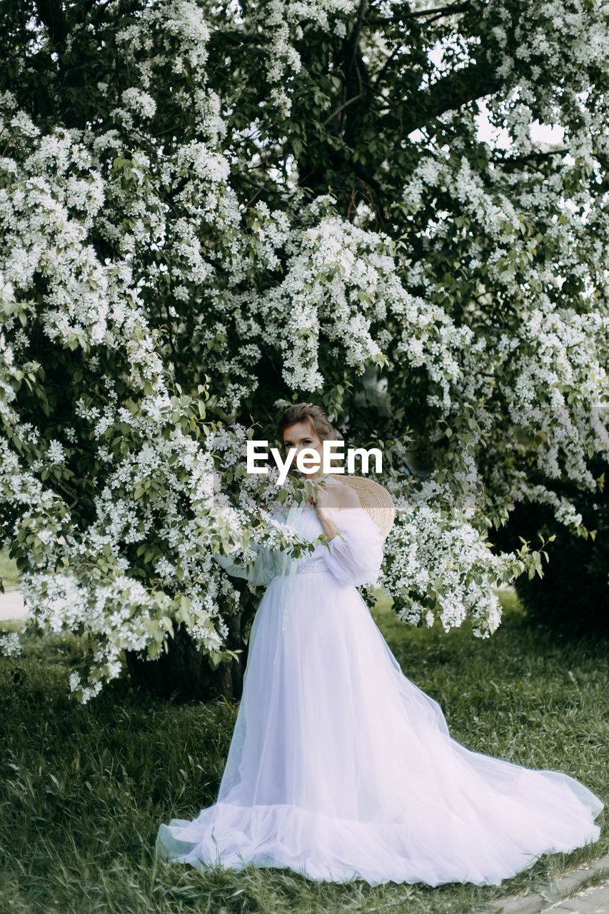 A beautiful delicate elegant woman bride in a wedding dress walks alone in a spring outdoor park