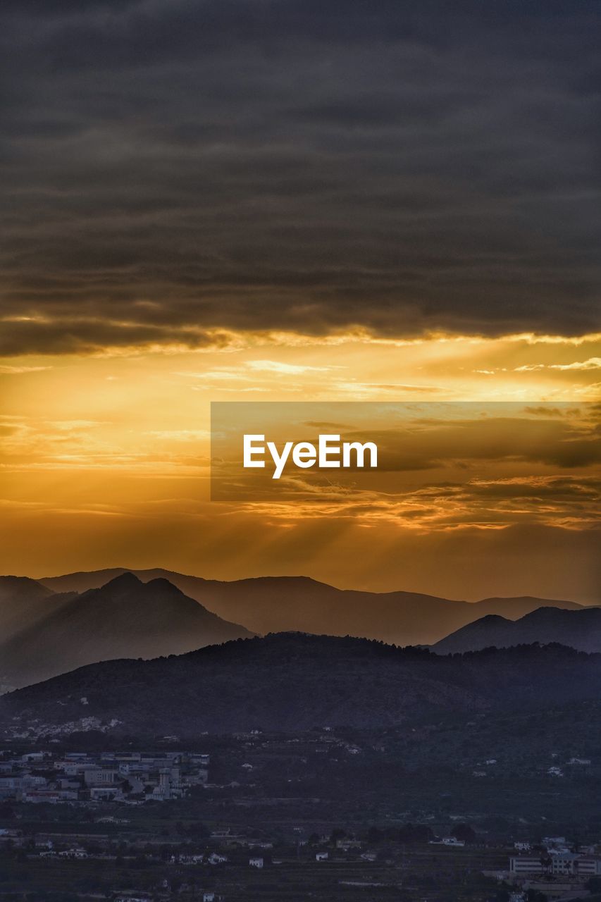 Scenic view of sea against dramatic sky during sunset